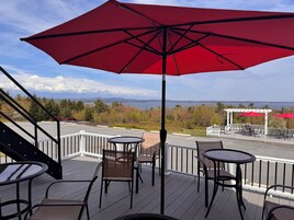 Una terraza con mobiliario exterior, vistas a un lago y un pabellón.