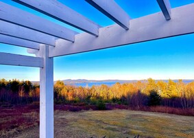 Una estructura de pérgola blanca con una vista despejada de un lago y montañas al fondo.
