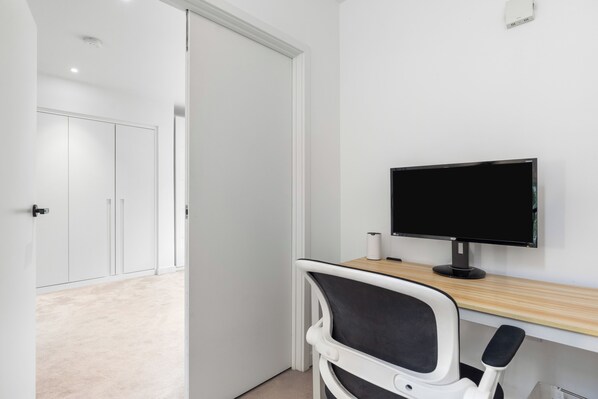 A modern office space with a desk, chair, and a computer monitor. - Experience the vibrant heart of London from our stylish 3bedroom, 2bathroom apt (London)