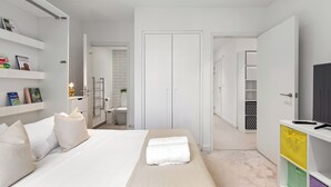 Een moderne slaapkamer met een bed, nachtkastjes, een kledingkast en een televisie.