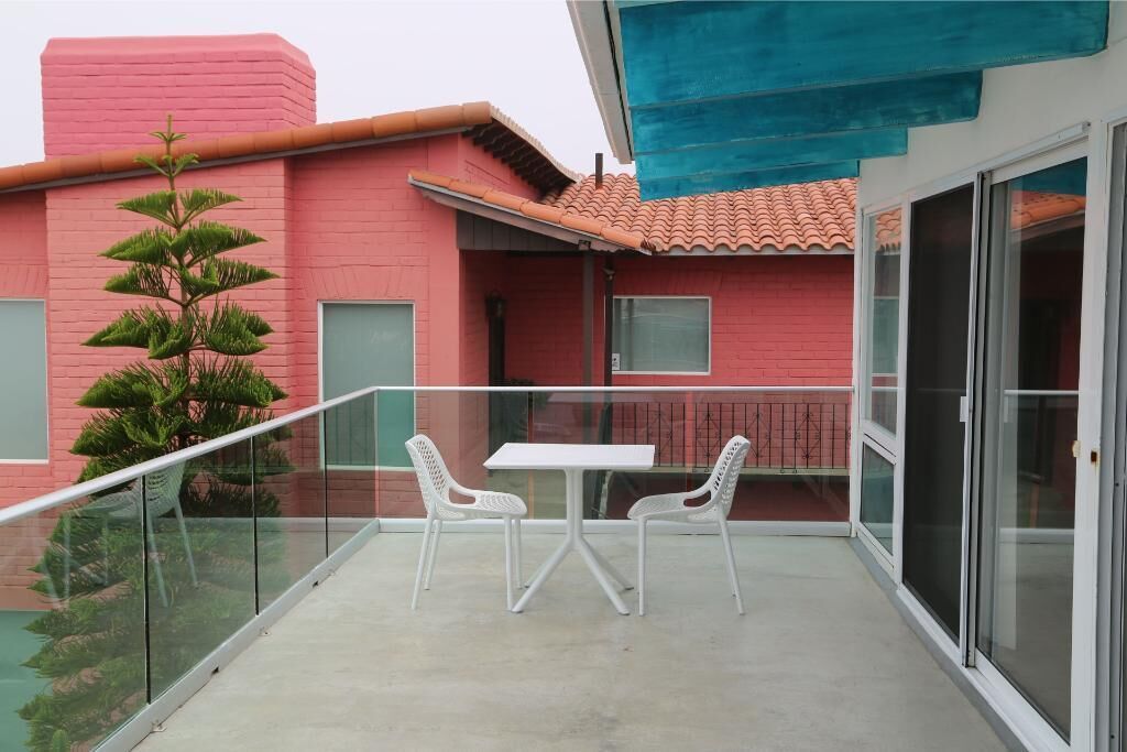 A balcony with a glass railing, a white table, and two white chairs.