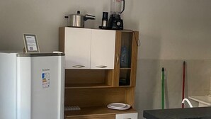 Ett kompakt kök med ett kylskåp, träskåp, en bänkskiva och ett handfat.