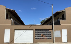 A building with two large garage doors, a row of windows on the ground floor, and a metal pole with wires. - Grand Maracanaú (Maracanau)
