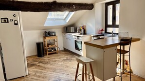Een kleine keuken met een houten aanrecht, een inbouwoven en een dakraam.