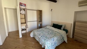 Een slaapkamer met een bed, een kledingkast en een plafond met zichtbare balken.