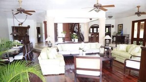 A spacious living room with a wooden floor, white sofas, a coffee table, and ceiling fans. - Rancho Utairs
 (La Romana)
