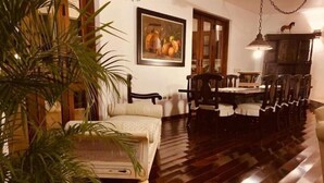 A dining area with a wooden table and chairs, a sofa, and a large potted plant. - Rancho Utairs
 (La Romana)