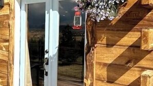 A wooden cabin with a glass door and a lantern hanging above it. - Spacious Mountain Chalet (Park County)
