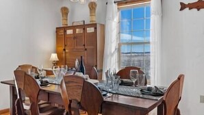 A dining area with a wooden table and chairs, a window with a view, and a cabinet with decorative items. - Spacious Mountain Chalet (Park County)