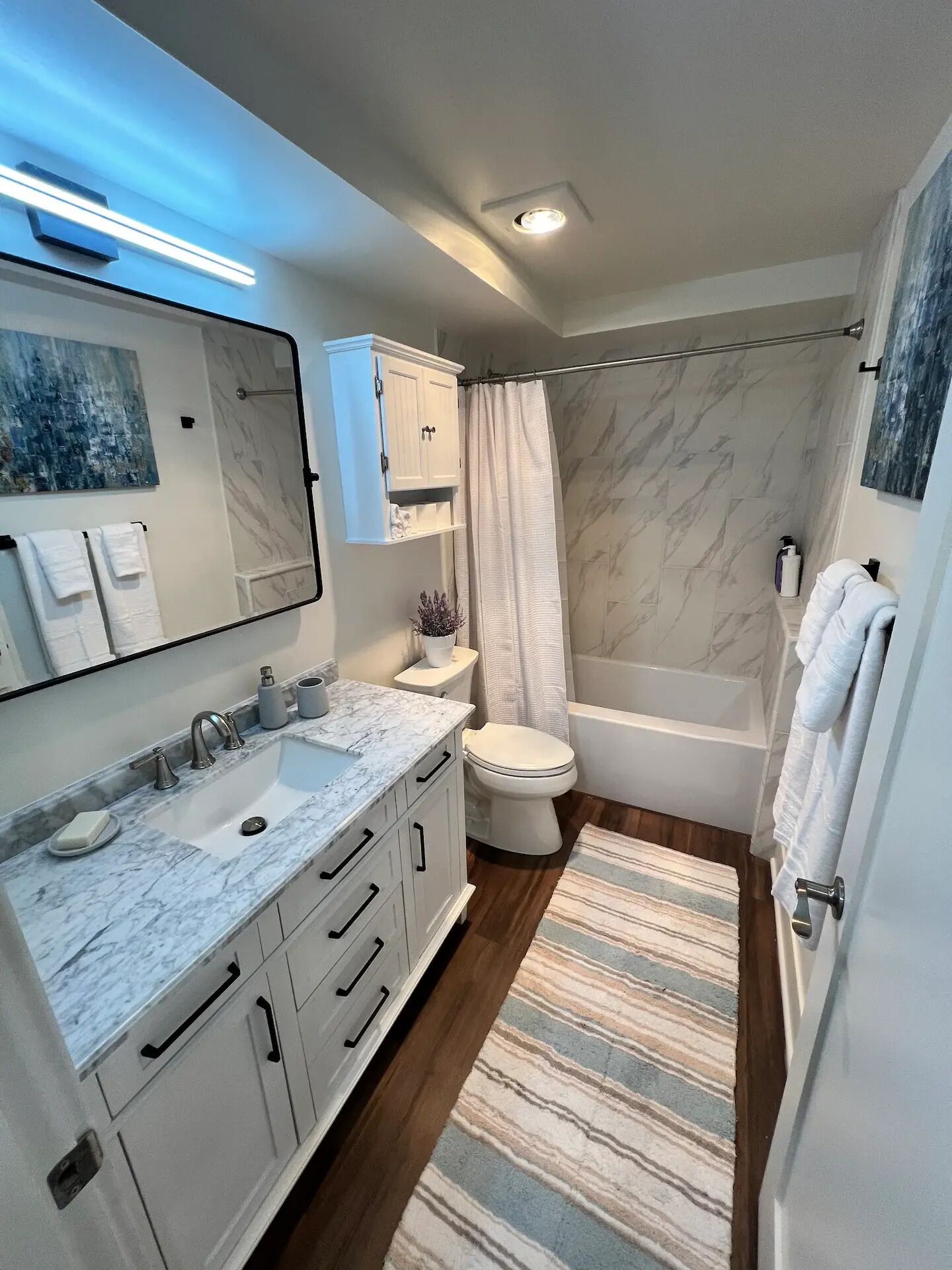 Un baño moderno con lavamanos de mármol, inodoro, bañera y cortina de ducha.