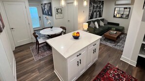 Una cocina moderna con una isla de mármol, suelo de madera y un comedor con mesa redonda y sillas.
