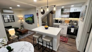 Una cocina moderna con una isla central, muebles blancos y electrodomésticos de acero inoxidable.