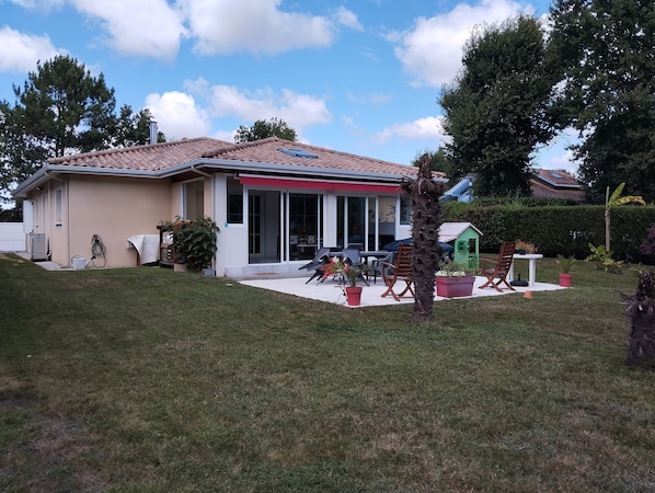 A single-story house with a tiled roof, a covered patio area, and a small playhouse in the backyard.