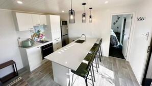A modern kitchen with a central island, stainless steel appliances, and pendant lighting. - Modern 2 Bedroom, 2 Bathroom Cottage with Farm Views (Bombay)