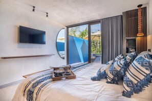 Un dormitorio moderno con una cama grande, un televisor montado y un ventanal corredizo que da a un espacio exterior con sombrillas.