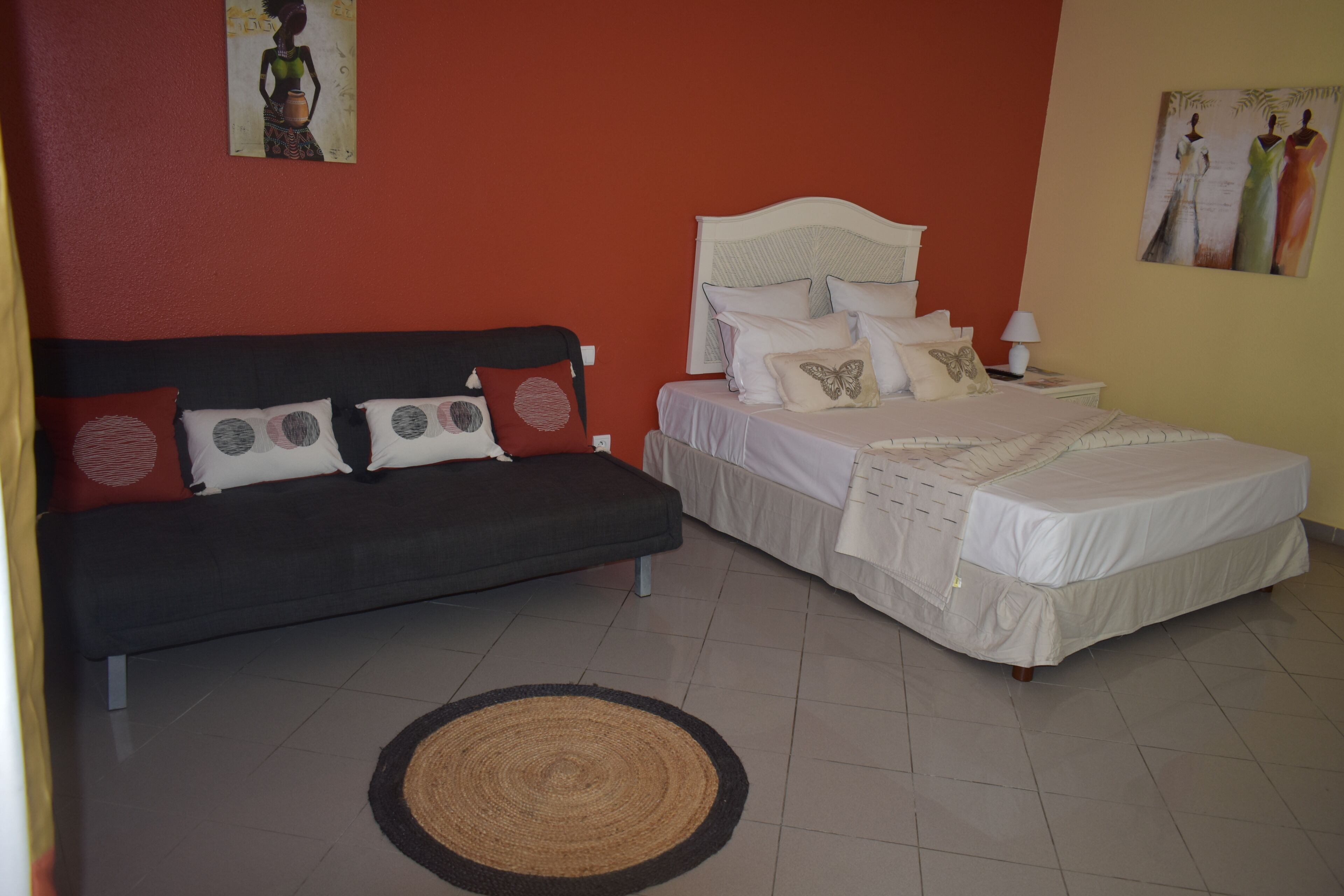 A bedroom with two beds, a sofa, and artwork on the walls.