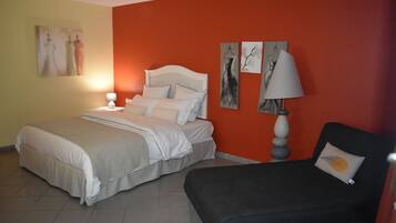 A bedroom with a bed, a bedside table with a lamp, and a chair.