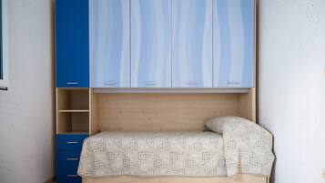 A bedroom with a bed, a blue wardrobe, and a wooden nightstand.