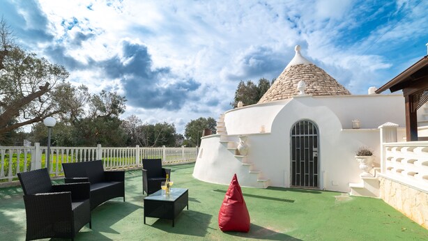 A patio with outdoor furniture, a red bean bag, and a white building with a conical roof.