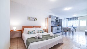 A hotel room with a bed, a desk, and a kitchenette.