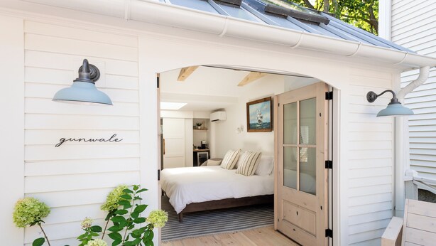 A cozy bedroom with a bed, a wooden door, and a small bathroom visible through an open door. - sisu, a boutique motel (Plymouth)
