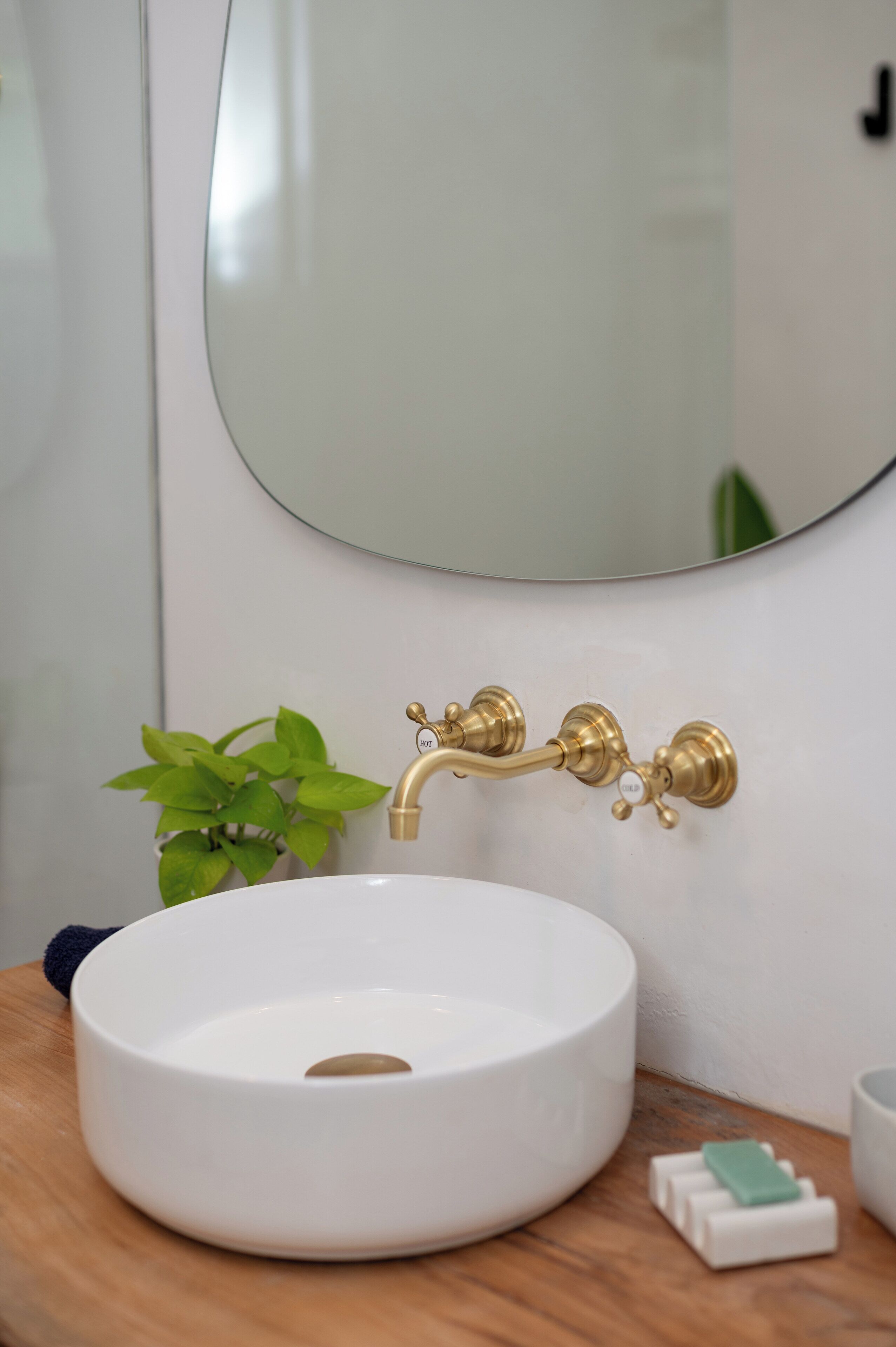 Un bagno con un lavandino bianco, un rubinetto dorato e uno specchio sopra.
