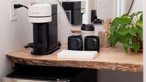 A compact kitchenette with a coffee maker, a small refrigerator, and a mirror reflecting the room. - sisu, a boutique motel (Plymouth)