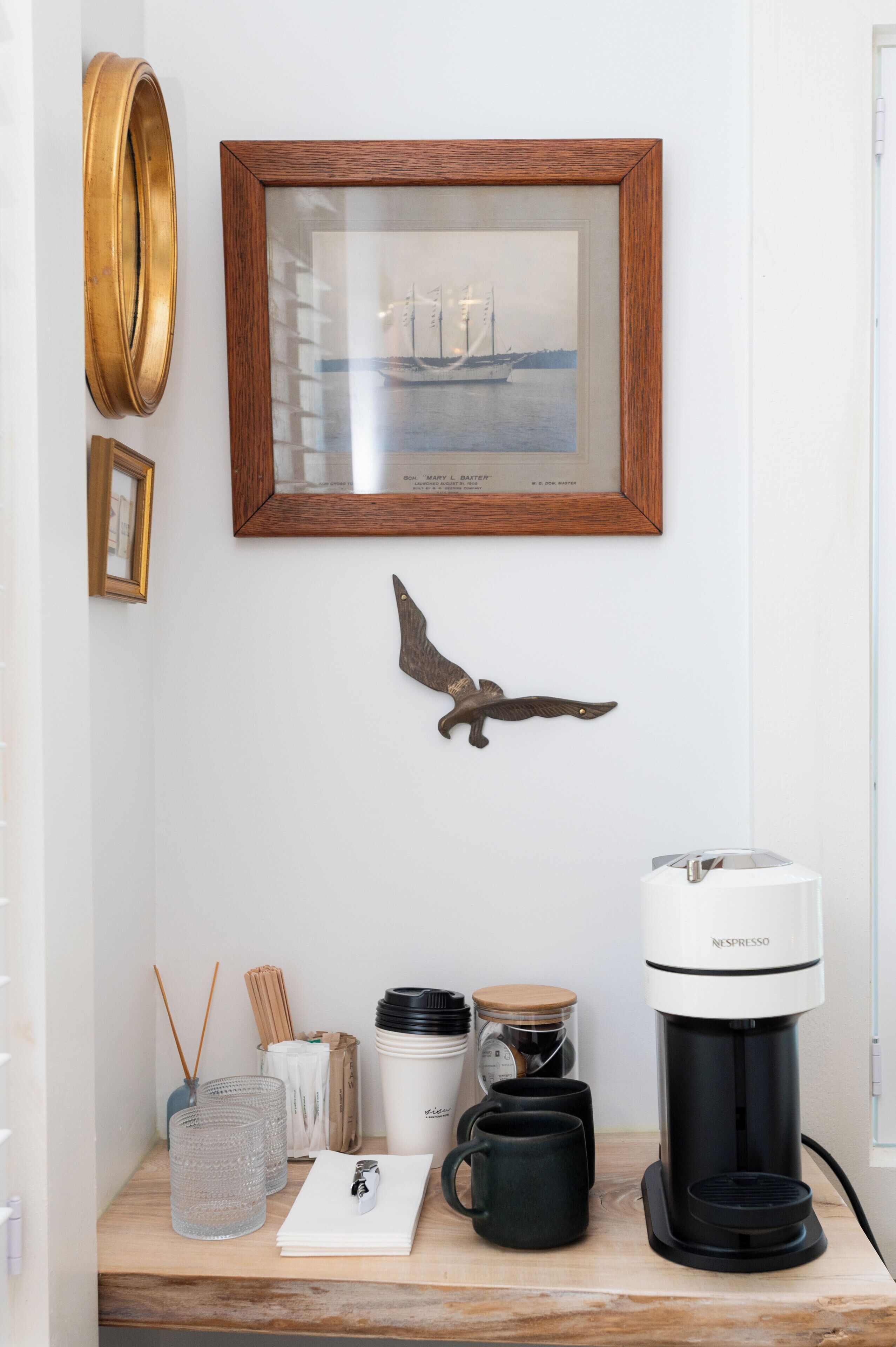 A coffee station with a Nespresso machine, a framed picture, and a decorative bird.