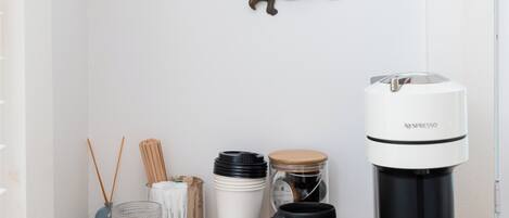 A coffee station with a Nespresso machine, a framed picture, and a decorative bird.