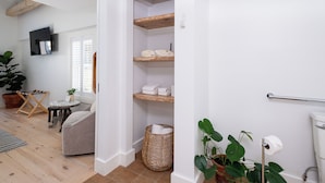 A modern bathroom with white walls, wooden shelves, a towel rack, and a toilet paper holder. - sisu, a boutique motel (Plymouth)