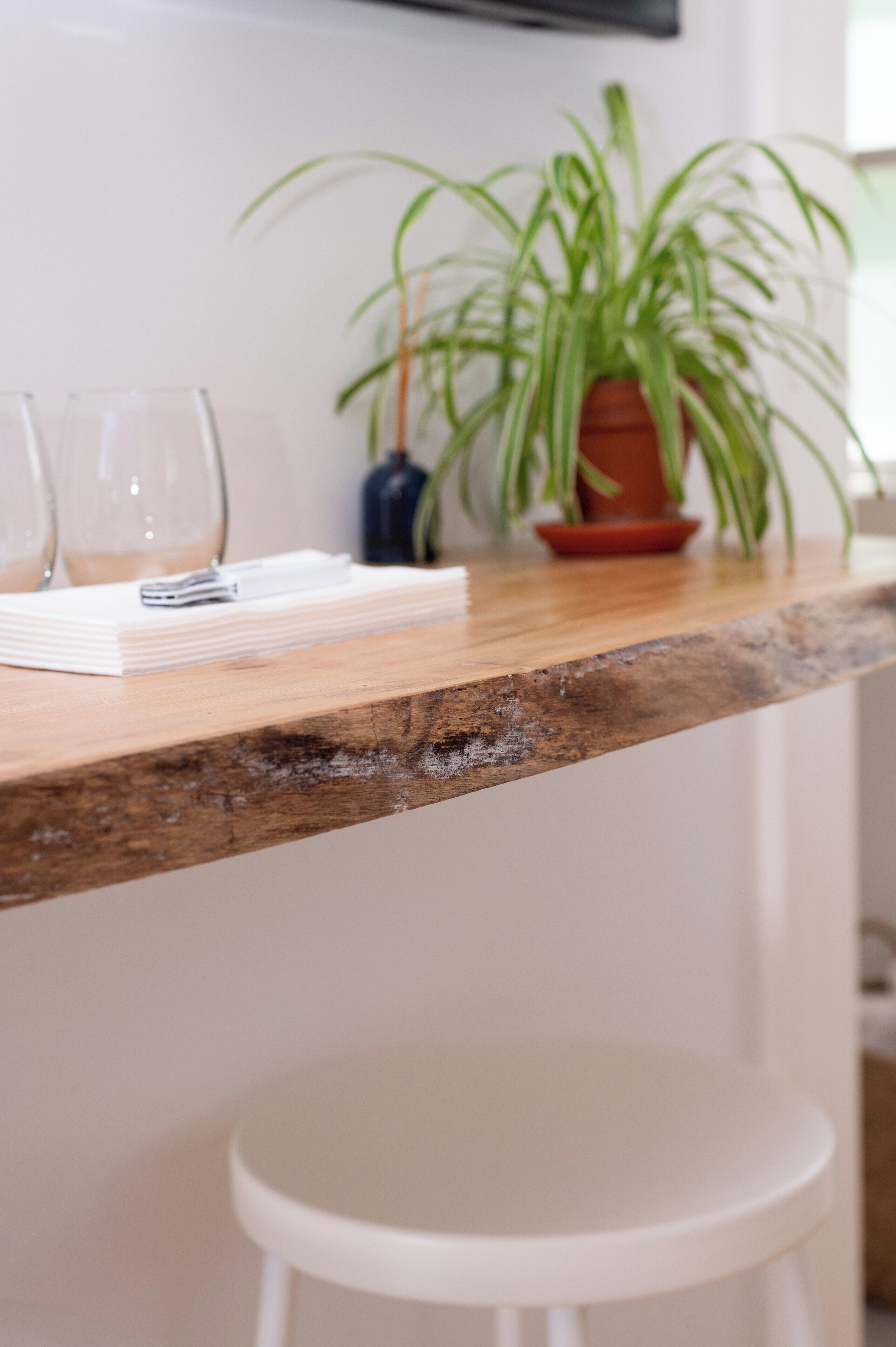 A kitchen counter with a potted plant, a stack of white napkins, and a few wine glasses.