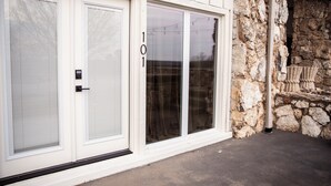 A building with a stone exterior, a garage door, and a large sliding glass door. - Suite 101 is the Main House's largest and most luxurious suite. (Cherokee Village)