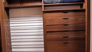 A wooden closet with a sliding door, a metal rod rack, and a set of drawers. - Suite 101 is the Main House's largest and most luxurious suite. (Cherokee Village)