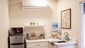 A compact kitchen with a refrigerator, coffee maker, and a water dispenser. - Suite 104 freatures a private outdoor-covered balcony. (Cherokee Village)