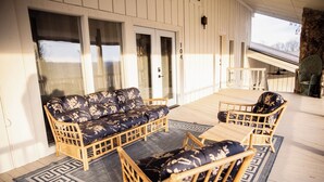 A covered outdoor seating area with a sofa and two chairs, a wooden deck, and a view of the outdoors. - Suite 104 freatures a private outdoor-covered balcony. (Cherokee Village)