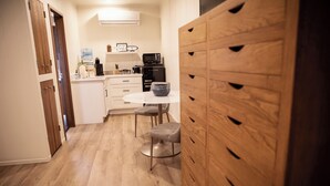 A kitchen with white cabinets, a microwave, a coffee maker, and a water dispenser. - Suite 105 freatures a private outdoor-covered balcony. (Cherokee Village)