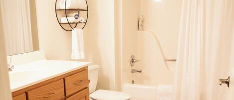 Une salle de bain comprenant des toilettes, une douche, une baignoire et un meuble-lavabo avec un miroir.