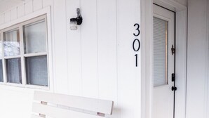 A white building with a bench outside, a door with the number 301, and a window with blinds.