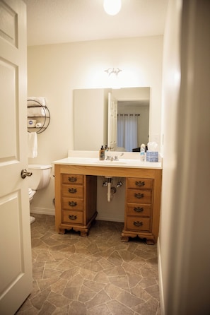 A bathroom with a white sink, wooden vanity with drawers, a mirror, and a towel rack.
