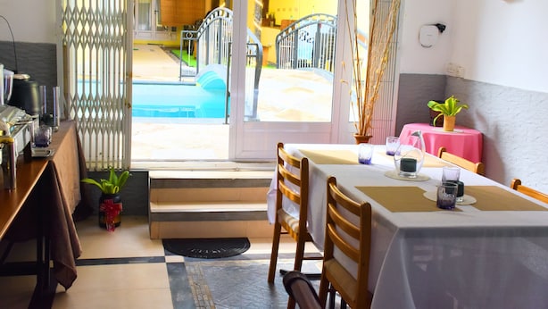 Un comedor con una mesa para dos, una planta en maceta y vistas al área de la piscina exterior.