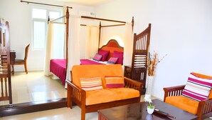 Una habitación con cama con dosel, un sofá, una mesa de madera y una silla.