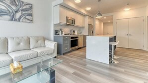 Una cocina moderna con una isla central, armarios blancos y electrodomésticos de acero inoxidable.