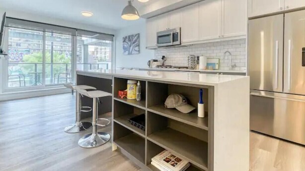 Una cocina moderna con armarios blancos, electrodomésticos de acero inoxidable y un taburete de bar.