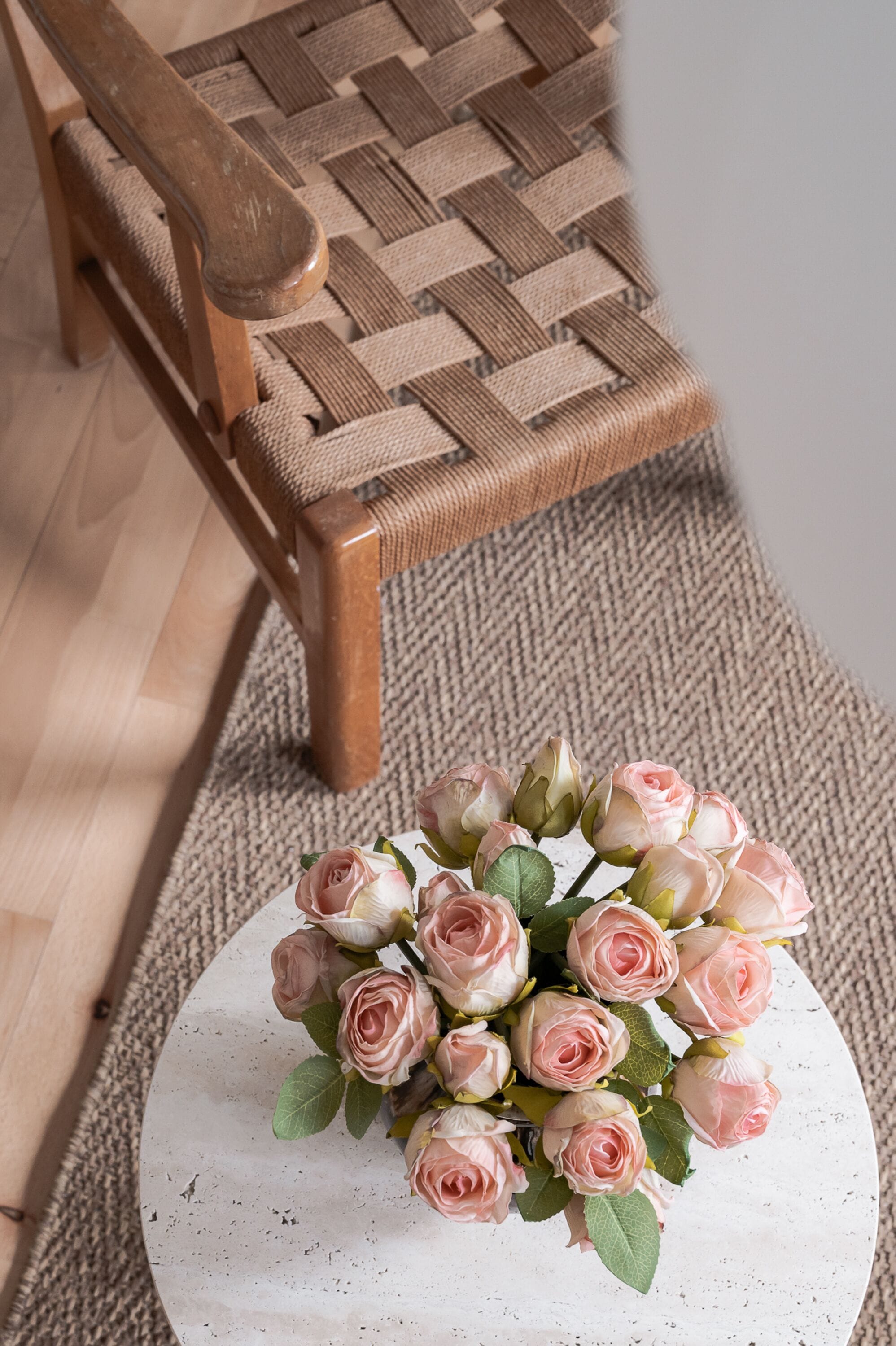 A round white table with a bouquet of pink roses.