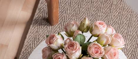 A round white table with a bouquet of pink roses.