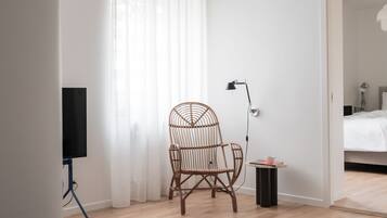 Una stanza con una sedia in vimini, una lampada da terra e un tavolino con una tazza.