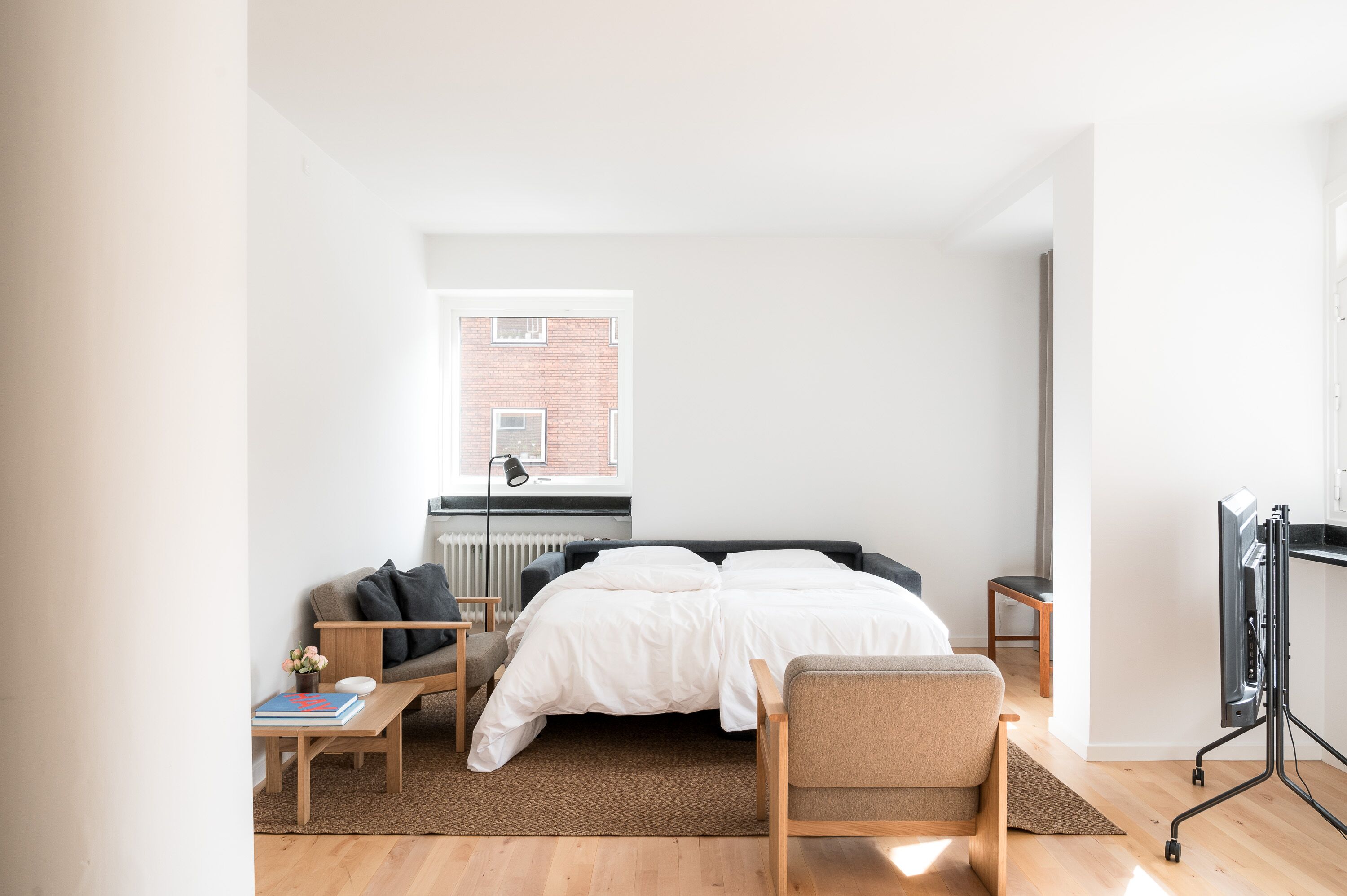 Une chambre moderne avec un grand lit, un bureau, une chaise et un meuble pour la télévision.