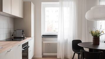 Une cuisine moderne avec des meubles blancs, un plan de travail noir et une fenêtre ornée de rideaux légers.