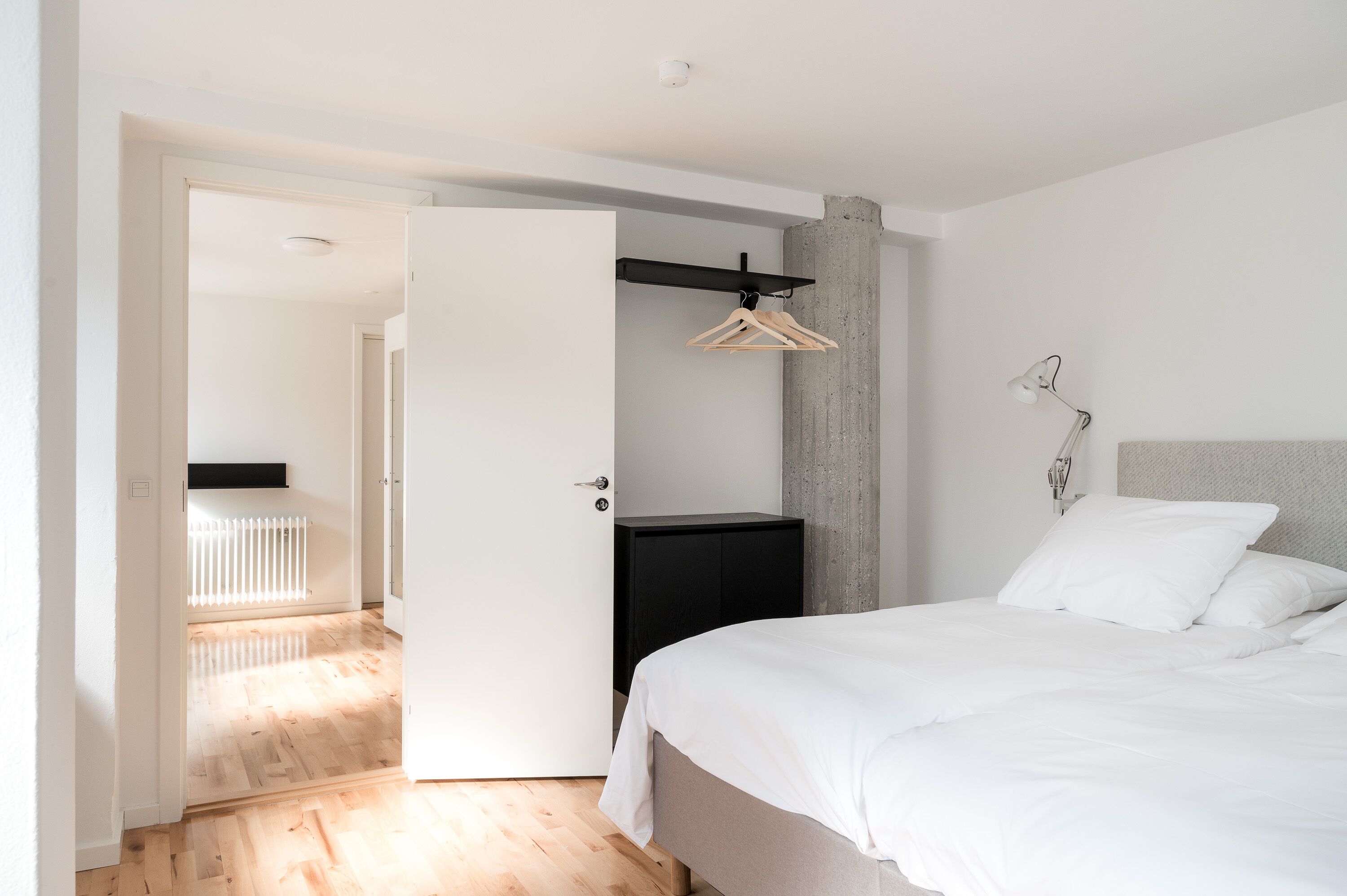 A modern bedroom with a bed, a wardrobe, and a hanging rack.