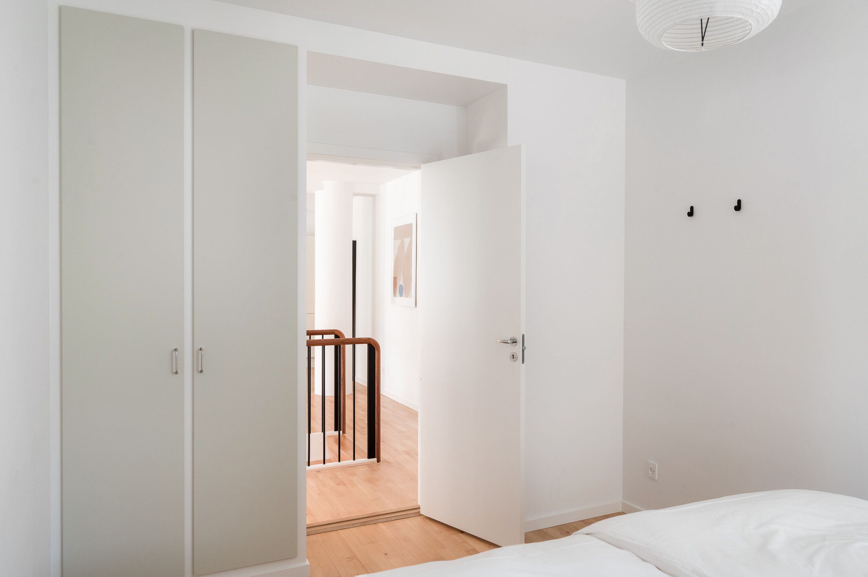 A bedroom with a bed, a wardrobe, and a door leading to a hallway.